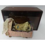 19th Century small doll with china head and shoulders and kid leather body with a rocking crib in