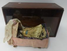 19th Century small doll with china head and shoulders and kid leather body with a rocking crib in