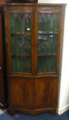 A reproduction mahogany serpentine corner cabinet.