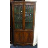 A reproduction mahogany serpentine corner cabinet.