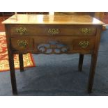 A Georgian mahogany lowboy with ornate brass handles.