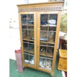 TALL GLAZED TWO DOOR OAK BOOKCASE WITH THREE ADJUSTABLE SHELVES ON CLAW AND BALL FEET