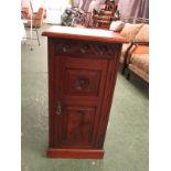 An Edwardian red walnut pot cupboard with foliate carved frieze, door with carved panel and walnut