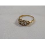 Gold ring set with a row of three diamonds, the largest central stone estimated at 0.25 carat, the