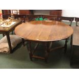 An early 19th century oak oval gate leg dining table with turned supports and plain rectangular