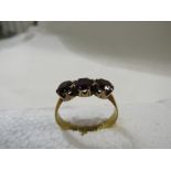 22ct gold ring set with three dark purple stones, British assay marks, 3.2g