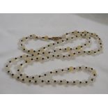 An onyx and freshwater pearl necklace spaced with black beads and with a 9ct gold clasp, length