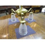 A brass electric ceiling light fitting, three scrolled arms from central bun with acorn drop,