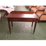 A Victorian mahogany two drawer side table with back rail, on tapering turned legs with white