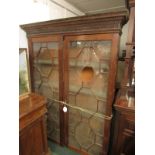 A mahogany bookcase with two geometrically glazed doors enclosing four internal shelves, dentil