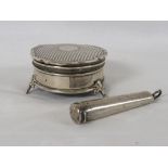 A silver round dressing table box with an engine turned hinged lid and standing on three feet,