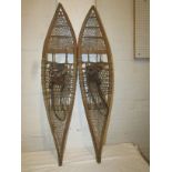 A pair of bent wood framed snow shoes with woven skin and leather straps, early to mid 20th century,