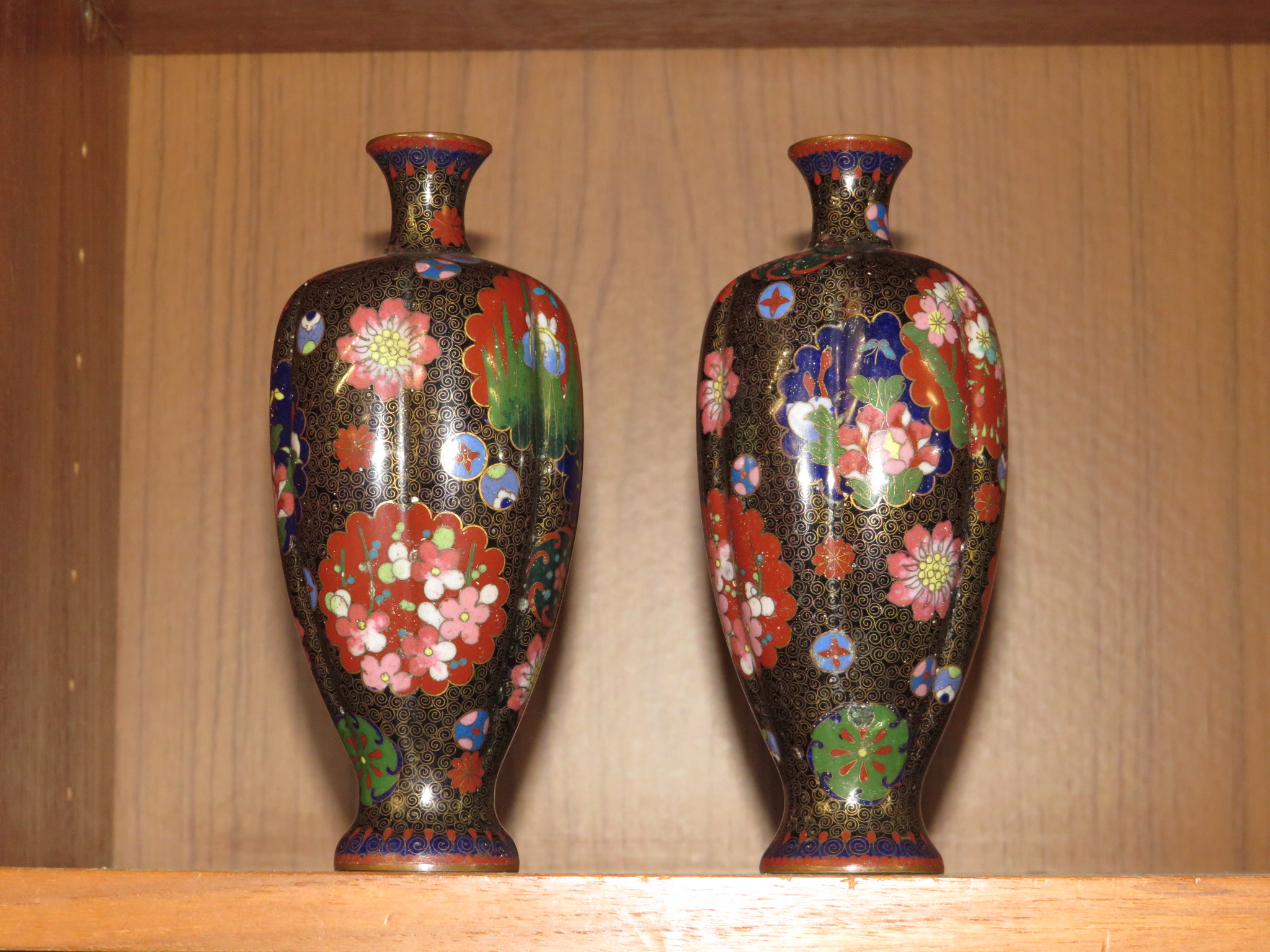 PAIR OF SMALL BLACK GROUND RIBBED CLOISONNE ENAMELLED VASES PATTERNED WITH VARIOUS FLOWERS AND