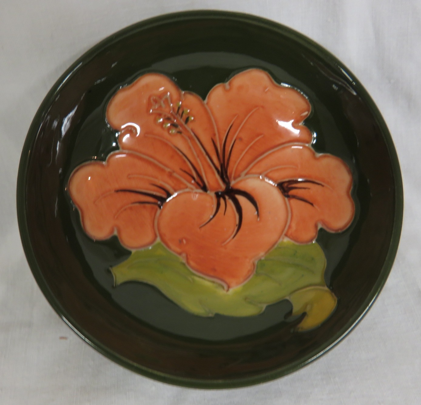 A small Moorcroft pottery hibiscus bowl, green ground with pink flower, height 4cm, diameter 11cm,