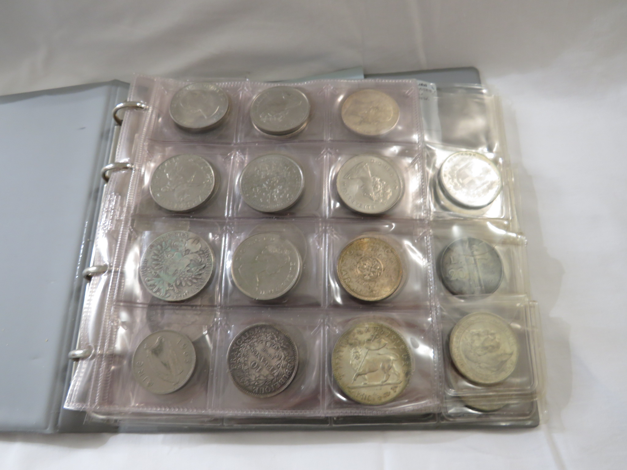 A black ring binder of crowns and silver, nickel silver and bronze foreign currency and other