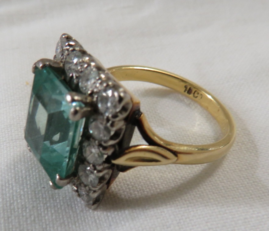 18ct gold ring set with an aquamarine (emerald cut 11.5mm x 10mm approximately) within a border of