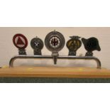 Five car badges mounted on a chromium bar and set on a pine plinth - Institute of Advanced
