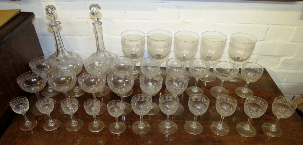 A suite of drinking glasses and a near pair of bottle shape decanters, all etched with key fret