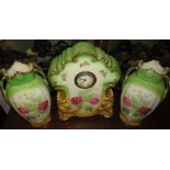 A circular Victorian mantel clock in a porcelain case with two garniture vases printed with rose