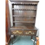 An early 19th century stained oak dresser, the upper section having three plate racks with wavy