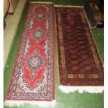 TWO RED GROUND PATTERNED FLOOR RUNNERS WITH TASSELLED ENDS