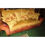 TAN LEATHER THREE SEATER SOFA WITH PALE GOLD UPHOLSTERED CUSHIONS AND PATTERNED SCATTER CUSHIONS