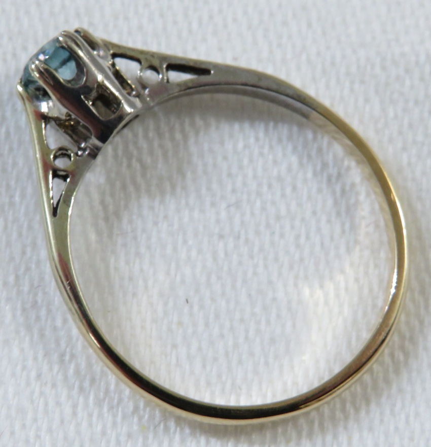 A dress ring set with an aquamarine (diameter 3.5mm), the shank stamped 9ct and toned white