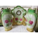 A circular Victorian mantel clock in a porcelain case with two garniture vases printed with rose