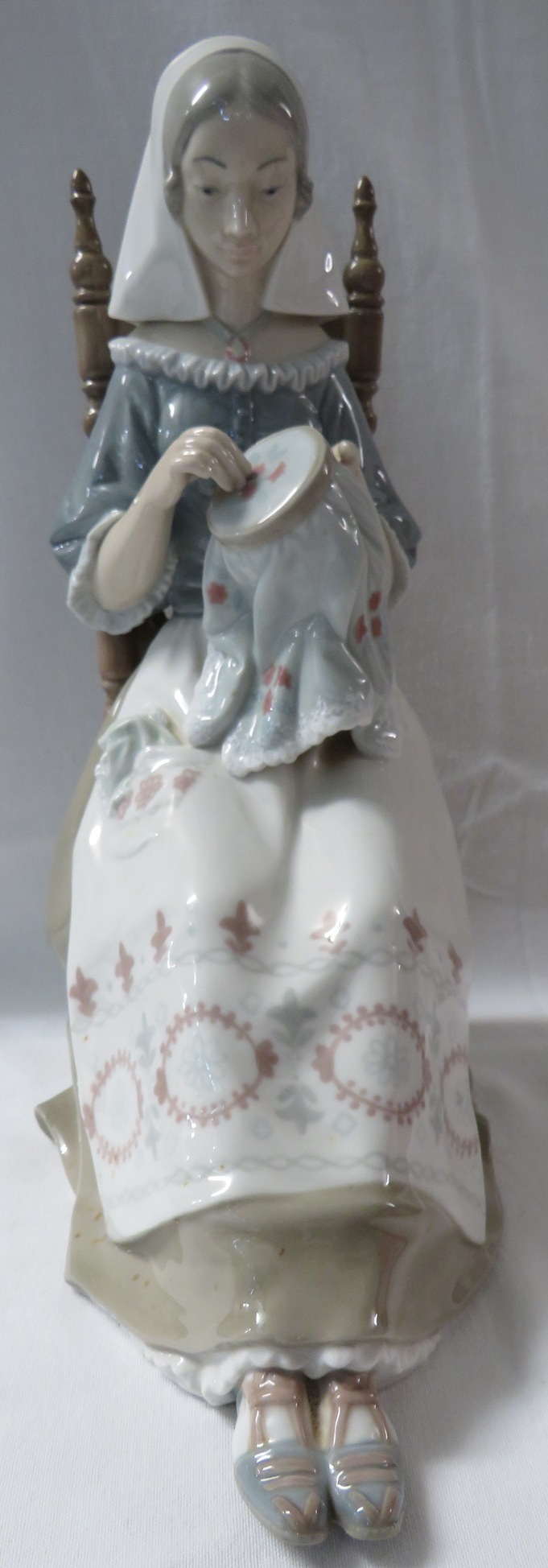 Lladro porcelain figure of a woman with embroidery seated on a spindle turned chair (height 28cm)