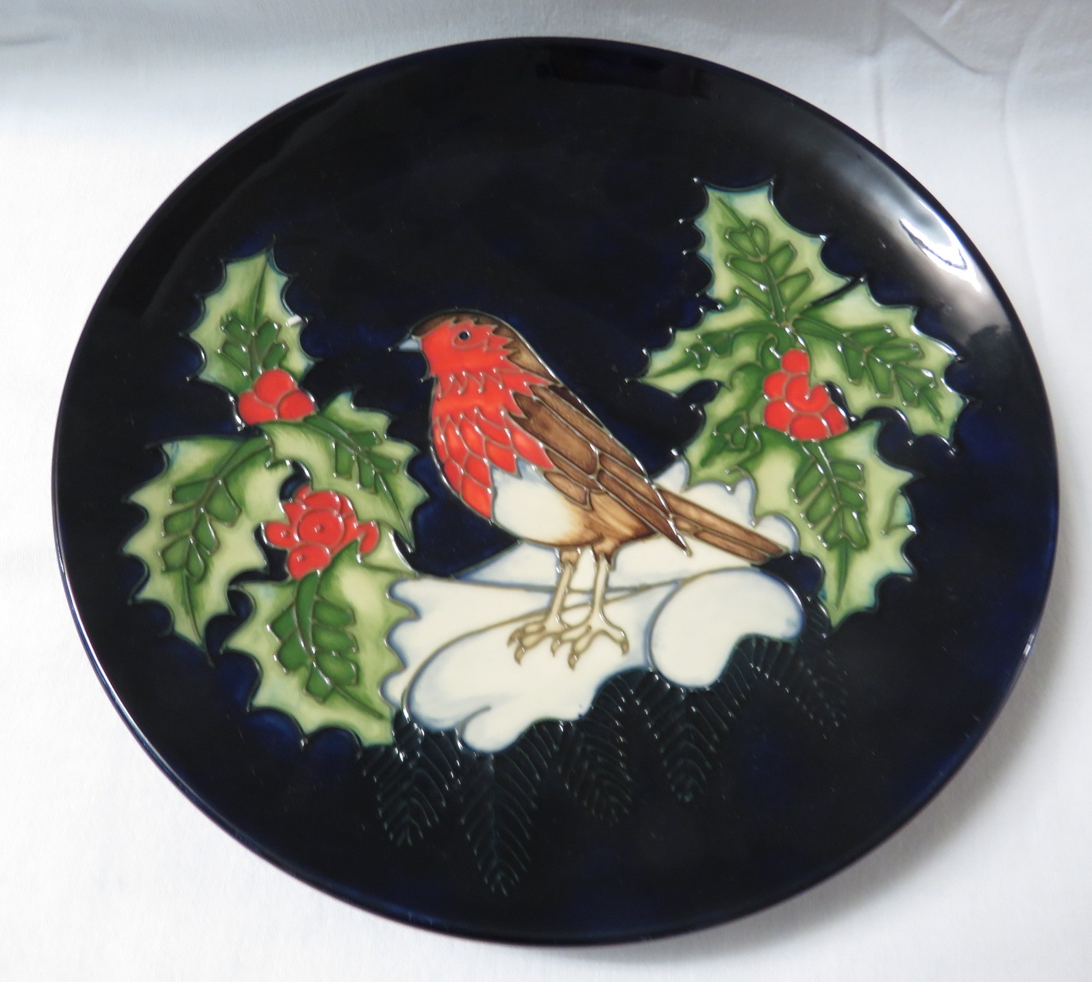 Moorcroft pottery Christmas plate, dark blue with robin, holly and snow, stamped MOORCROFT MADE IN