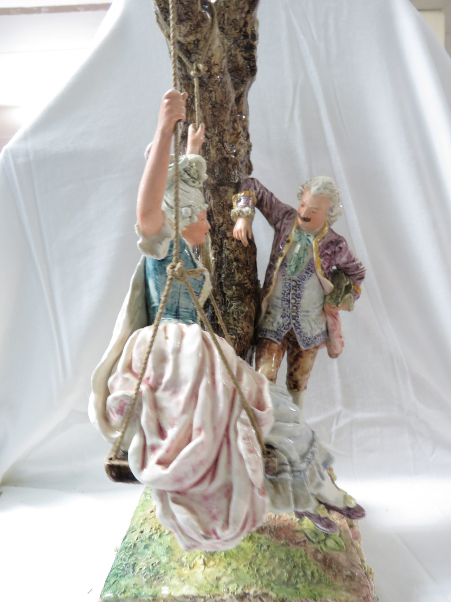 A large polychrome glazed pottery model of a lady in a swing seat suspended from a tree with - Image 3 of 5