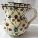 A floral pottery milk jug marked Liberty London, cream ground and painted with a trellis pattern