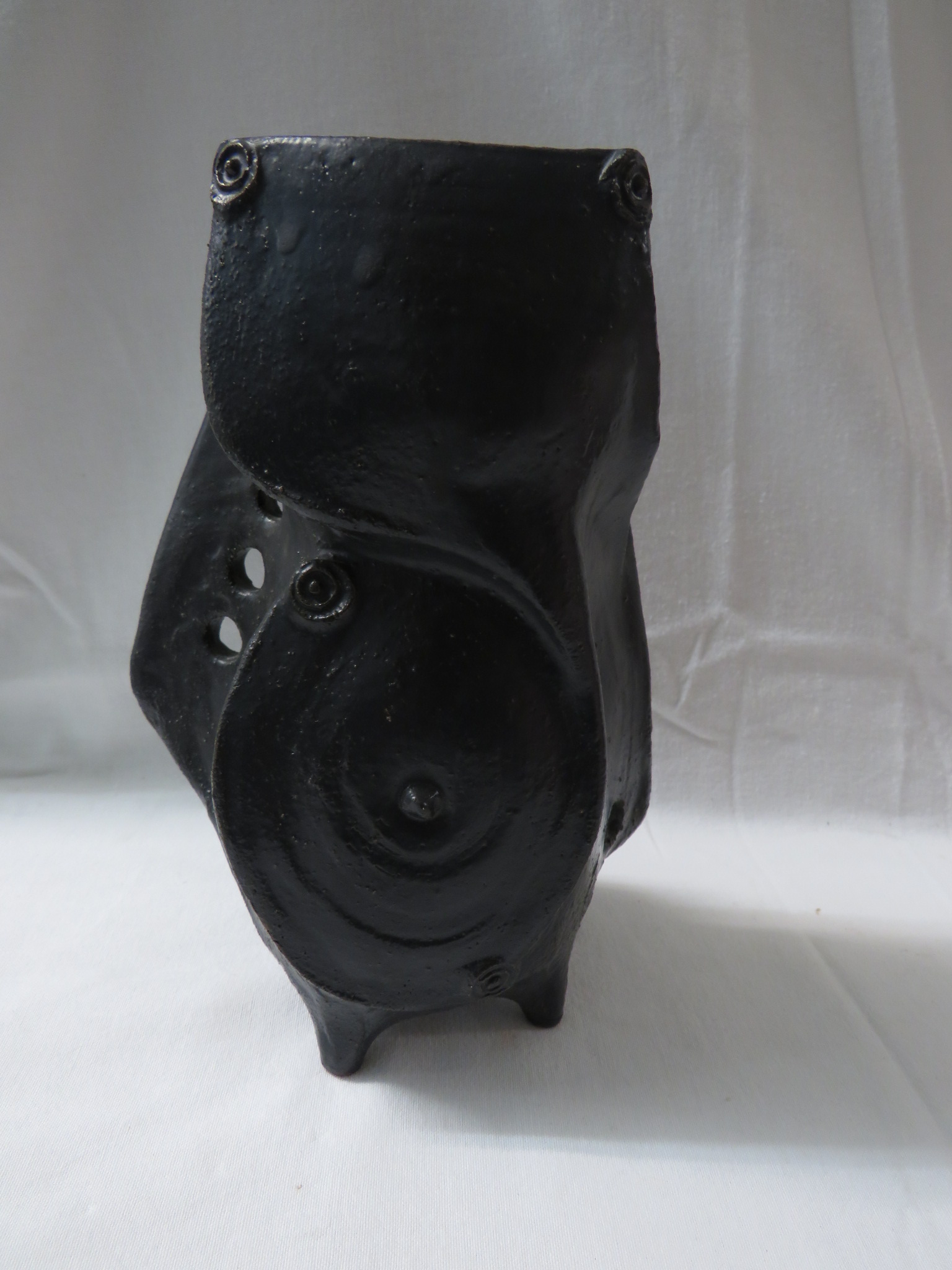 Pottery vase of abstract form in a black glaze with flanges and excised circles, standing on four - Image 2 of 3