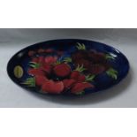 Moorcroft pottery oval dish, blue ground painted with red and maroon poppies, stamped MOORCROFT MADE