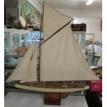 A model of a single masted yacht with four canvas sails, length from prow to stern 102cm, height