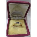 Yellow metal ring set with solitaire sapphire between a line of six small white stones, the shank