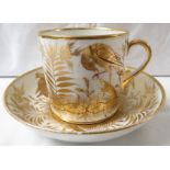 A 19th century porcelain cup and saucer gilded with birds and flowers