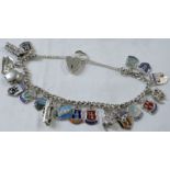 A white metal charm bracelet of nineteen charms with a British hallmarked silver heart shaped