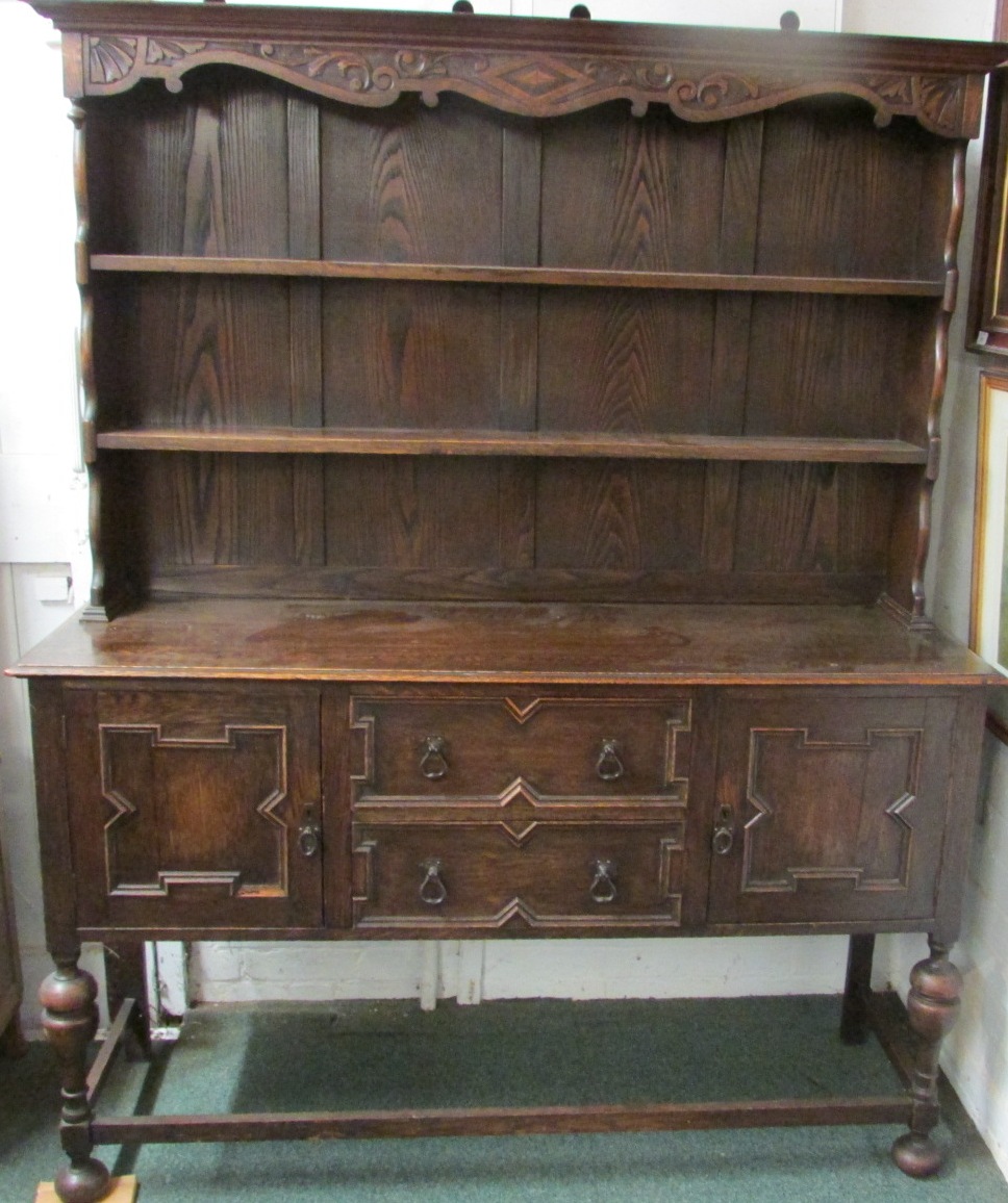 An oak dresser with carved frieze and two plate shelves to top and two drawers with single