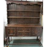 An oak dresser with carved frieze and two plate shelves to top and two drawers with single