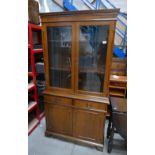 A reproduction oak display cabinet with two glazed doors above two drawers, two door base on bracket