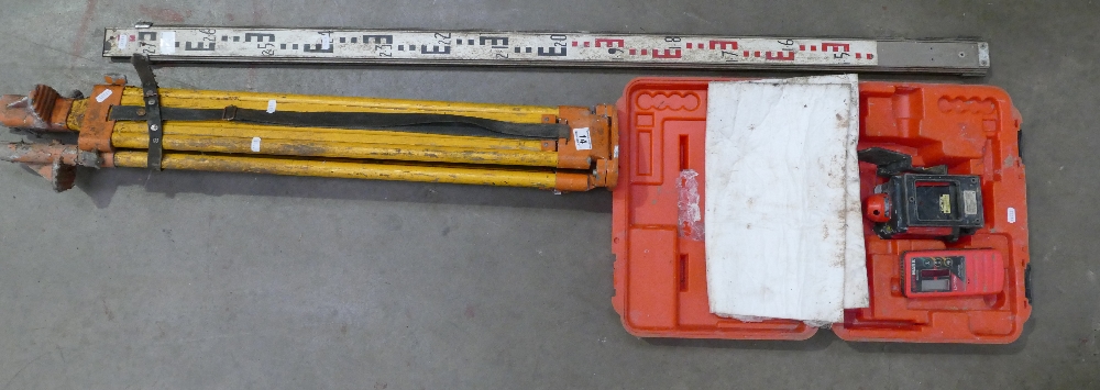 A laser level together with a wooden tripod base. (2)