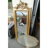 A reproduction rectangular gilt mirror with beval edge and cherub design with a similar oval mirror.