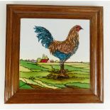 Tube lined pottery tile decorated with a cockerell in oak frame as stand, overall 29.5 x 29.