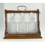 Edwardian oak cased tantulus with three cut glass decanters,