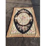 A French au basin style tapestry, with oval floral panel framed by black border, the spandrels