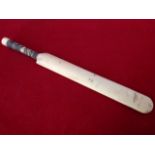 A Victorian ivory letter knife carved in the form of a cricket bat, with tapering ribbed handle.