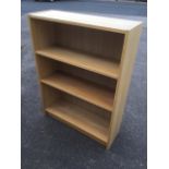 A modern oak bookcase with adjustable shelves, supported on a plinth.