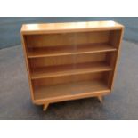 A 60s oak bookcase with rectangular top above sliding glass doors enclosing shelves, raised on