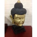 A buddha head, with gilt face and beaded hair, mounted on square plinth. (24in)